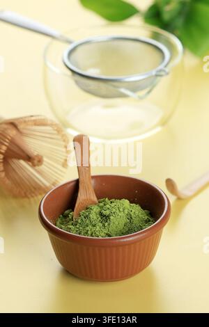 Matcha-Grüntee-Pulver mit Sieb, Matcha-Schüssel und Chasen-Whisk auf gelbem Hintergrund Stockfoto