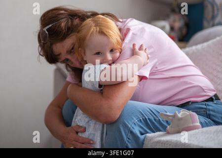Enkelin umarmt ihre Großmutter mit einem Lächeln im Gesicht Stockfoto