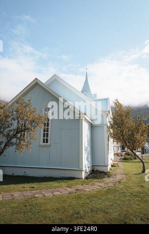 Seyðisfjarðarkirkja, die Blaue Kirche, in Seyðisfjörður Island, unter den umliegenden Berghängen, August 2026 Stockfoto
