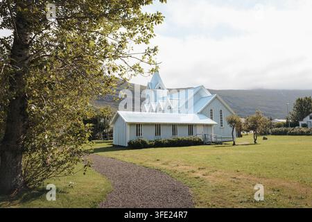Seyðisfjarðarkirkja, die Blaue Kirche, in Seyðisfjörður Island, unter den umliegenden Berghängen, August 2026 Stockfoto