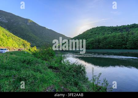 Wunderschöne Bergkette mit einem Fluss, der hindurchfließt. Das Wasser ist ruhig und der Himmel ist klar Stockfoto