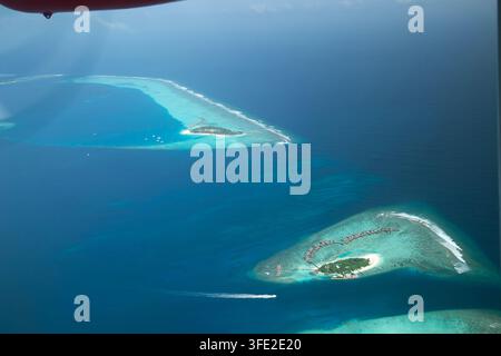 Ein atemberaubender Hochwinkel-Aerialblick auf paradiesische tropische Inseln, Wasser-Villen und lebendige Korallenriffe, umgeben von tiefblauem und klarem Tur Stockfoto
