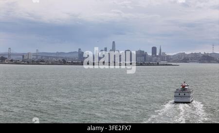 Luftaufnahme der Skyline von San Francisco mit der Bay Bridge im Hintergrund und einem Fährboot, das auf der Bucht in San Francisco, Kalifornien, segelt, Unite Stockfoto