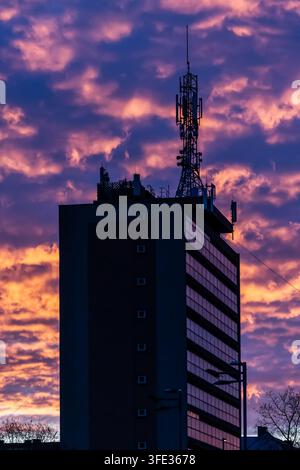 Hohes Gebäude mit Antennen und dramatischem Himmel im Hintergrund Stockfoto