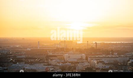 Luftaufnahme der Stadtlandschaft von Helsinki während eines goldenen Sonnenuntergangs mit dunstigem Licht über den städtischen Dächern und Gebäuden von Kallio in Helsinki, Uusimaa, Finnland Stockfoto