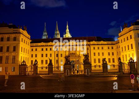 Beleuchtete Hauptfassade der Prager Burg, gesehen vom Hradčanské Platz, mit Kathedraltürmen, die dahinter aufragen. Stockfoto