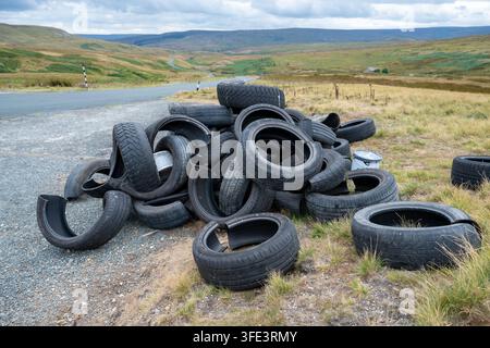 Haufen alter Reifen, die auf einem Rastplatz an einer Landstraße in den Yorkshire Dales, UK, entsorgt wurden. Stockfoto