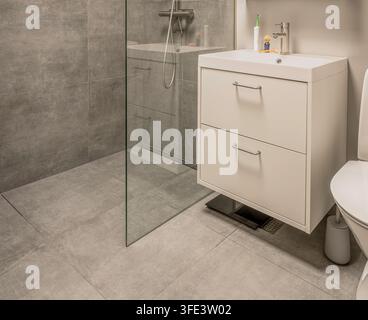 Nordisches Badezimmerdesign mit weißem minimalistischem Waschtisch und grauen Steinfliesen Stockfoto