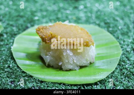 Nahaufnahme von thailändischem Klebreis mit goldenem Kokos-Pudding auf einem frischen grünen Bananenblatt, ein traditionelles süßes Dessert in Thailand. Stockfoto