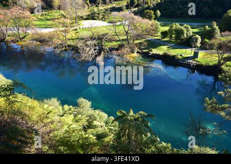 Diese Hochwinkel-, malerische Ansicht zeigt einen breiten, ruhigen Fluss, der sich unter hellem Sonnenlicht durch eine üppige Landschaft schlängelt. Der Fluss dominiert das Untere... Stockfoto
