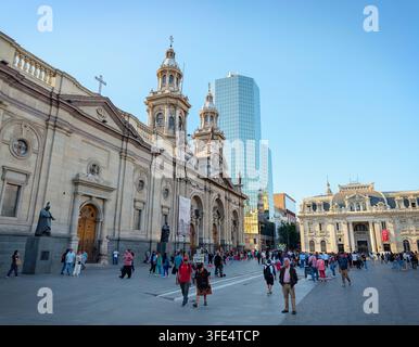 SANTIAGO, CHILE - 03. DEZEMBER 2025: Menschen gehen an der historischen Metropolitankathedrale von Santiago und dem modernen Glaskoloss an der Plaza de Armas vorbei Stockfoto