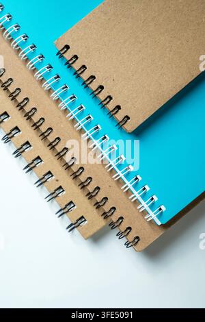 Eine Luftaufnahme zeigt eine Vielzahl von blauen und braunen spiralgebundenen Notizbüchern in verschiedenen Größen, ordentlich auf einer weißen Oberfläche angeordnet Stockfoto