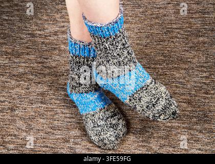 Füße in gestrickten Wollsocken. Warme hausgemachte Socken Stockfoto
