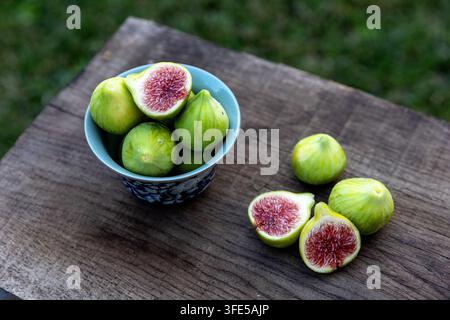 Frische ganze und geschnittene Feigen, wunderschön angeordnet in und um eine antike chinesische Porzellanschale, schaffen ein elegantes künstlerisches Stillleben. Stockfoto