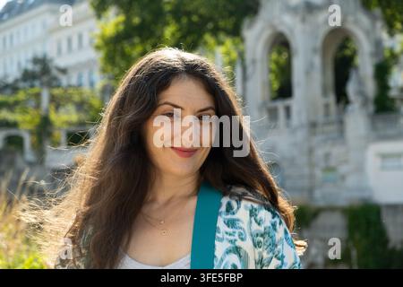 Nahaufnahme eines Porträts einer schönen brünetten Frau mittleren Alters, die im sonnigen Tageslicht lächelt Stockfoto