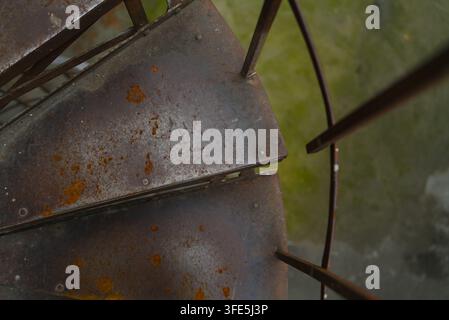 Schaut man hinunter auf alte rostige Metallstufen einer Wendeltreppe, die verwitterte Textur und industrielle Details zeigen. Stockfoto
