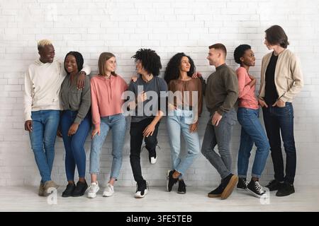 Sorglose, multirassische Gruppe von Freunden, die drinnen zusammen chillen Stockfoto