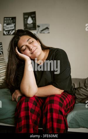 Frau sitzt mit geschlossenen Augen entspannt auf dem Bett zu Hause Stockfoto