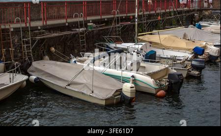 Motorboote, die entlang einer Uferpromenade an einem Hafenwall festgemacht sind. Eine kleine Marina repräsentiert Freizeitschifffahrt, Wassertransport. Stockfoto