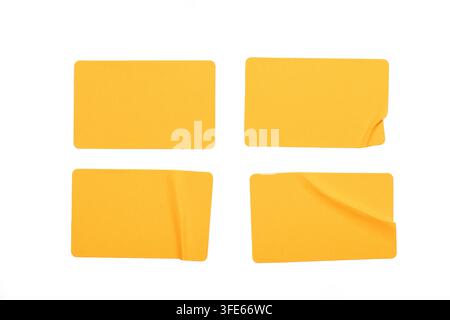 Satz von vier gelben Papieraufklebern, isoliert auf weißem Hintergrund. Realistische Papiertextur mit Falten, Knickstellen und gewellten Ecken. Stockfoto