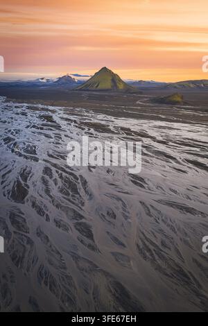 Luftaufnahme des Vulkans Maelifell, umgeben von komplexen gewundenen Flussmustern und vulkanischen Ebenen unter einem lebendigen Sonnenuntergangshimmel in Skaftarhreppur, Island Stockfoto