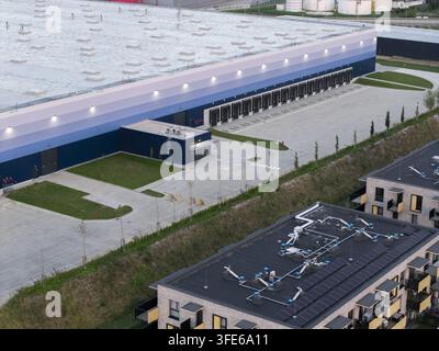 Luftbild eines modernen Logistikstandorts und Terminals mit mehreren Ladedocks, einem großen Lagerhaus und einem angrenzenden Wohnkomplex Stockfoto