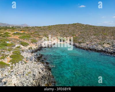 Luftbild einer abgeschiedenen Bucht mit türkisfarbenem Wasser, umgeben von felsigen Klippen und mediterranem Buschland in Chania, Griechenland. Stockfoto