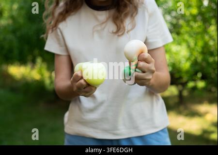Mittelaufnahme eines Kindes, das zwei weiche Kawaii-Dumpling-Squishies in beiden Händen hält, während es an einem sonnigen Tag im Park spielt. Stockfoto