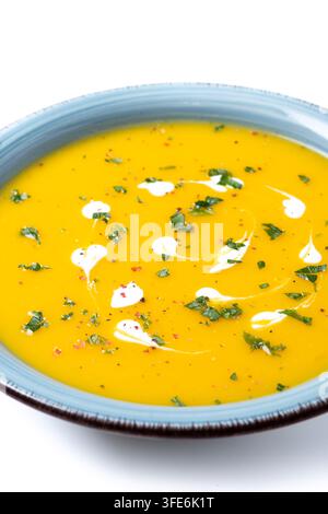 Cremige Kürbissuppe mit Kräutern und Sahne in blauer Schale isoliert auf weißem Hintergrund Stockfoto