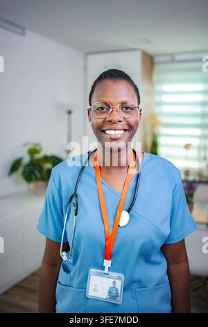 Afroamerikanischer medizinischer Fachkraft lächelt, trägt blaue OP-Kleidung und Stethoskop Stockfoto