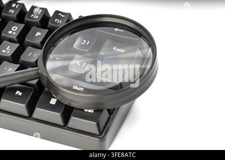 Lupe, die auf die Eingabetaste einer schwarzen Tastatur zoomt, und steht für sorgfältige Überprüfung vor der Bestätigung digitaler Aktionen. Stockfoto