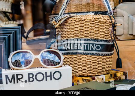 Designer-Stroh-Taschenhandtasche und Sonnenbrillen, die in einem Boutique-Modegeschäftsfenster in Reus, Katalonien, ausgestellt sind. Stockfoto