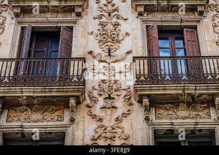 Detaillierte geschnitzte Steinreliefs und historische geschlossene Balkone an einer verzierten verwitterten Fassade in Reus, Katalonien. Stockfoto