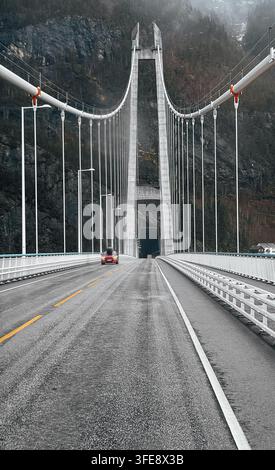 Eine niedrige, zentrale Perspektivenaufnahme, die die leere Asphaltstraße der ikonischen Hardanger-Hängebrücke in Norwegen hinunterblickt Stockfoto