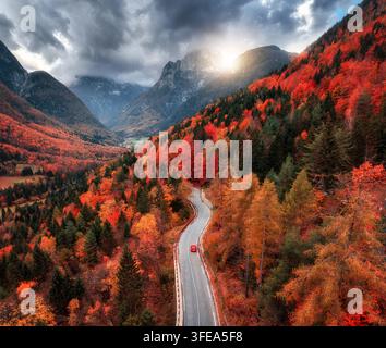 Aus der Vogelperspektive auf die gewundene Bergstraße im Wald bei Sonnenuntergang. Herbst Stockfoto