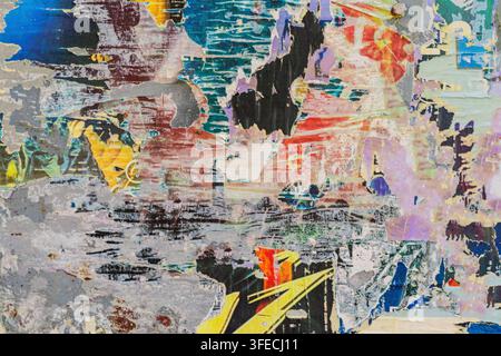Bunte abgerissene Posterschichten an einer urbanen Wand. Abstrakte Schichten aus abgerissenen und verwitterten Postern, bunte urbane Oberfläche. Verwitterte Papiertextur erzeugt Stockfoto