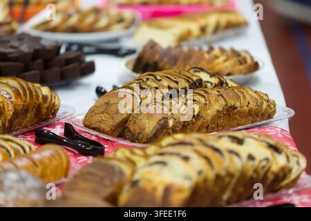 Verschiedene geschnittene süße Brote, Babka und Gebäck auf Tabletts auf einem festlichen Feiertags-Dessertbuffet-Tisch arrangiert. Stockfoto