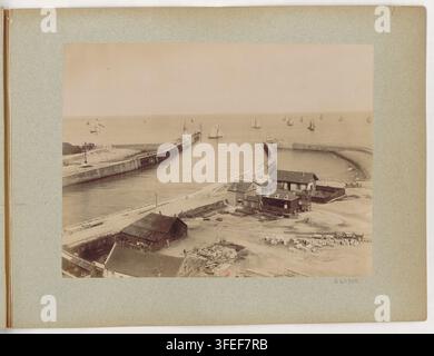 Eine Fotografie aus dem späten 19. Jahrhundert eines Küstenhafens in der Normandie, Frankreich, von James Valentine, einem schottischen Fotografen, die einen gebogenen Steinmolen, kleine Boote, einen Pier und niedrige Holzgebäude an einem sandigen Ufer zeigt Stockfoto