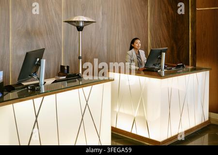 Hispanische Empfangsdame arbeitet an einem Computer in der Hotellobby Stockfoto