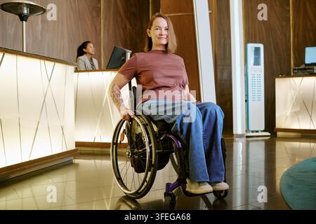 Porträt einer Frau mit Behinderung im Rollstuhl in der Hotellobby Stockfoto