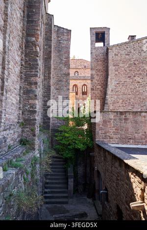 Eine ruhige architektonische Ansicht zeigt eine Treppe, die zu einem versteckten Garten führt, eingerahmt von verwitterten Steinmauern. Stockfoto
