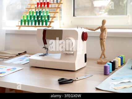 Nähmaschine mit Schneiderbedarf auf dem Tisch im Atelier Stockfoto