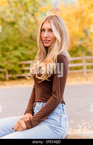 Schöne junge Frau, die im Herbstpark zurückblickt Stockfoto
