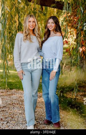 Zwei junge Frauen lächeln unter einer Trauerweide Stockfoto
