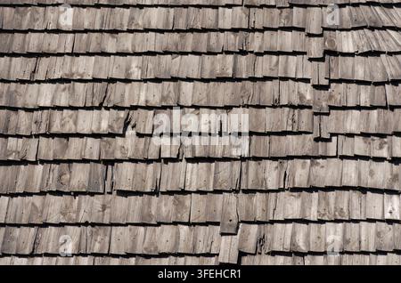 Nahaufnahme eines gealterten Holzschindeldachs aus überlappenden natürlichen Holzstücken, das rustikale Textur und traditionelle Handwerkskunst für Erbe zeigt Stockfoto