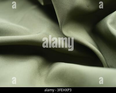 Nahaufnahme eines drapierten olivgrünen Stoffmusters mit glatten, weichen Falten und feinen Webdetails. Stockfoto