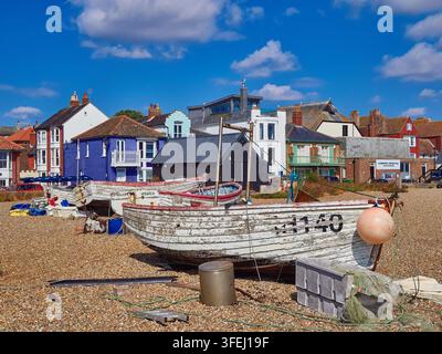 Verwitterte Fischerboote am Kieselstrand in der Küstenstadt Aldeburgh mit historischen, farbenfrohen Küstenhäusern Stockfoto