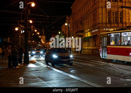 Verkehr in der Nacht und eine Prager Straßenbahn passieren das historische Slavia Café an der Masaryk-Uferpromenade in der Nähe des Nationaltheaters. Stockfoto