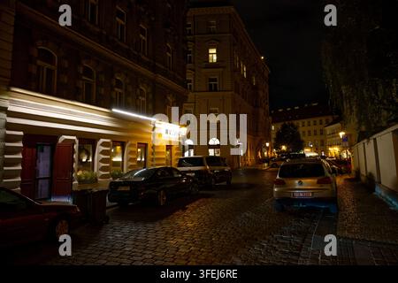Nachtansicht entlang einer Kopfsteinpflasterstraße in der Nähe des Bethlehemer Platzes mit beleuchteten Restaurants und historischen Gebäuden in der Prager Altstadt. Stockfoto