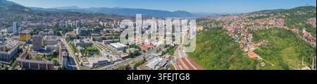 Breite panoramische Hochaufnahme über Sarajewo, die die Eisenbahninfrastruktur, Marijin Dvor, Novo Sarajevo und ein dicht bebautes Wohngebiet zeigt Stockfoto